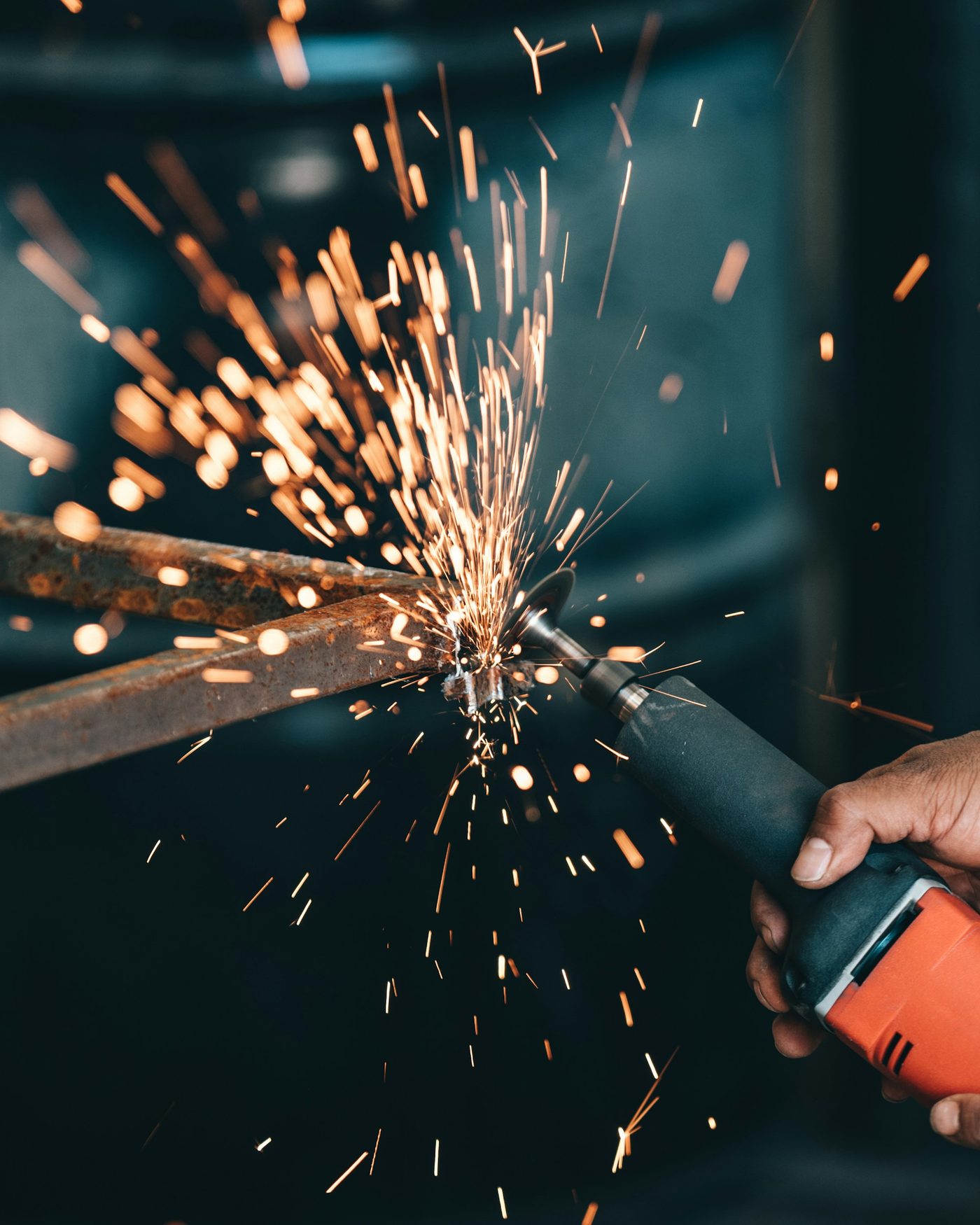 A person using an angle grinder on a piece of metal, sending sparks flying