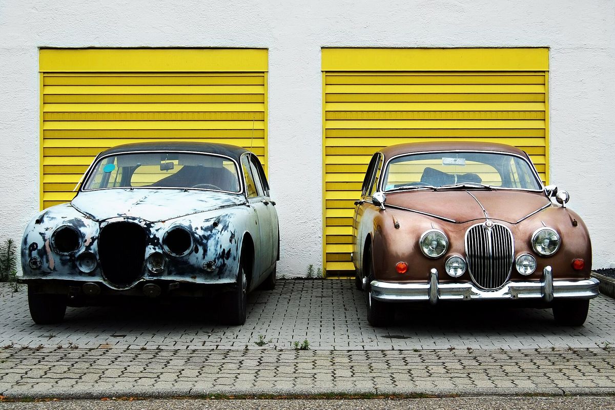 Two classic cars side by side, one in bare-metal preparation and one with a finished paint coat