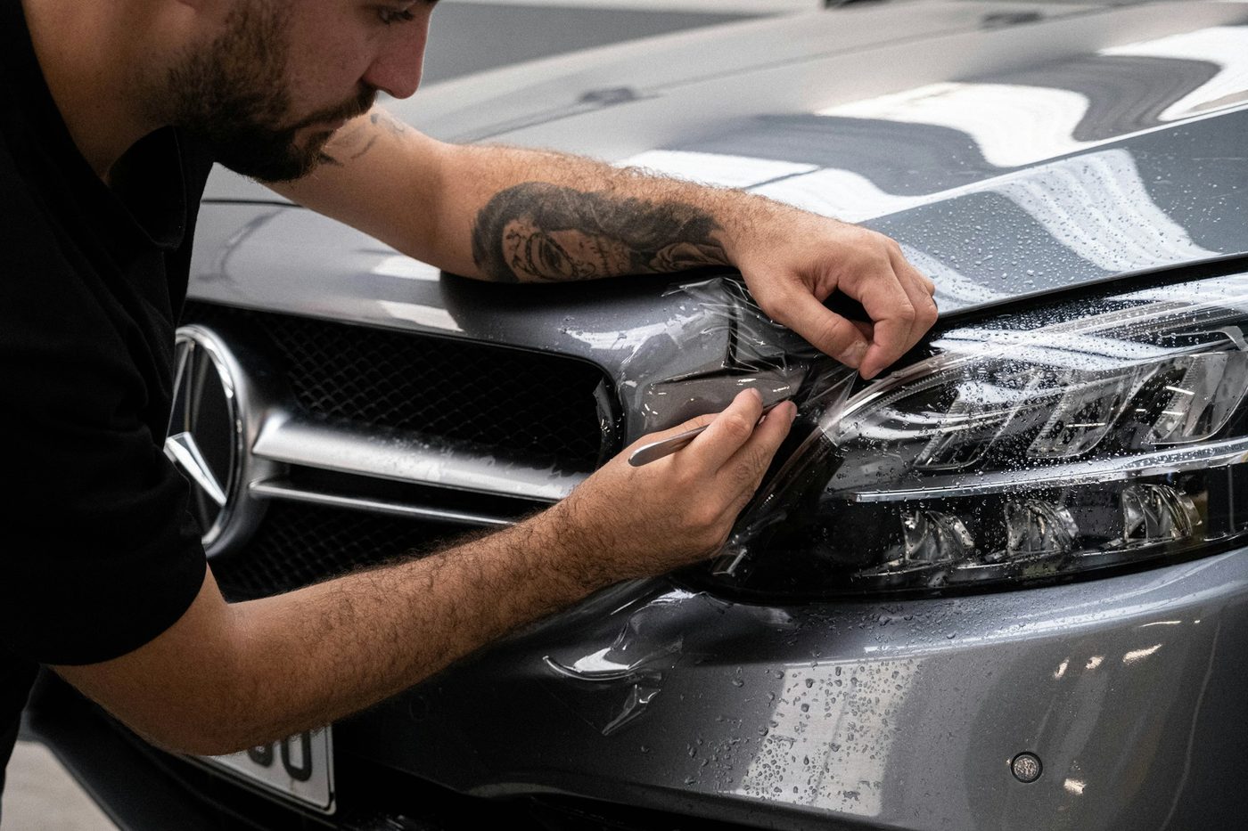 A man applying wax to the hood of a car by hand with a foam applicator pad