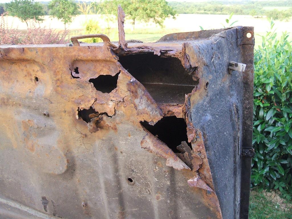 Close-up of heavy corrosion and rust holes eating through a car chassis frame rail