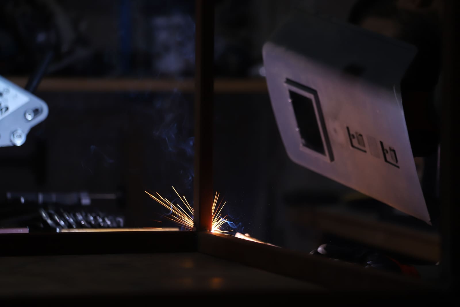 Close-up of a MIG welder joining metal, sparks flying in a workshop