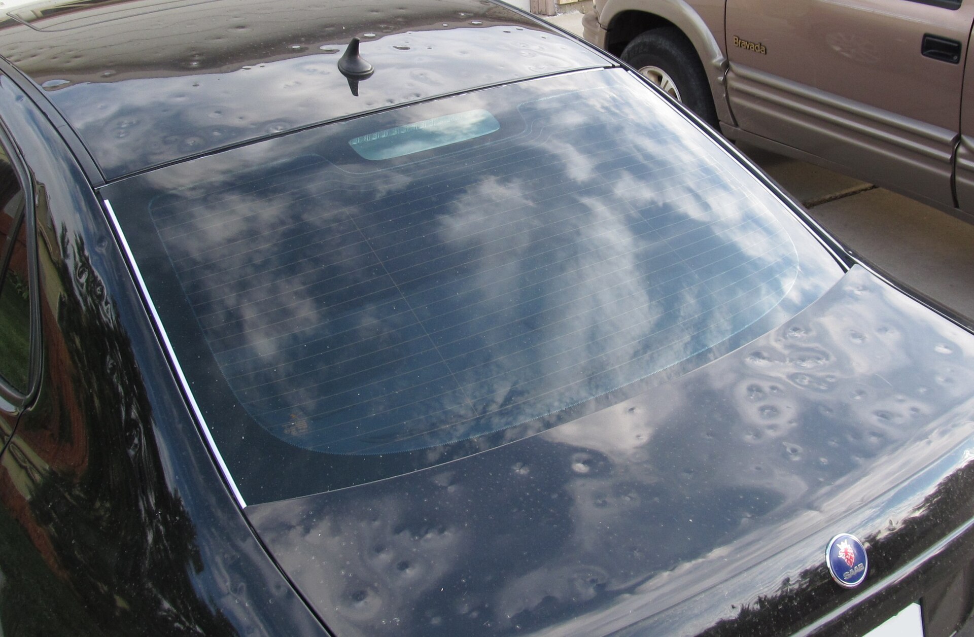 Dozens of small round hail dents across a car's rear body panel