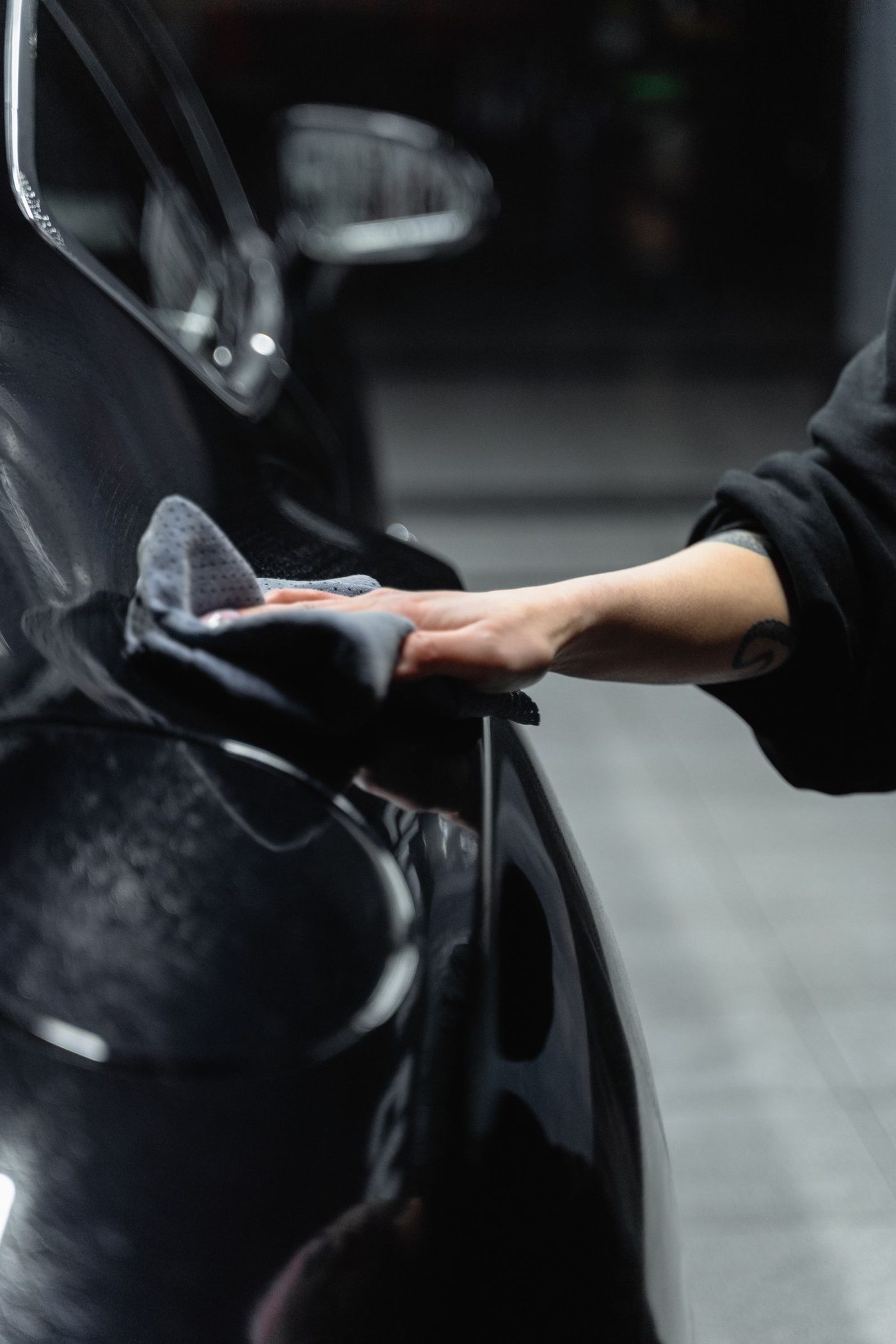 A close-up of a hand cleaning and polishing a car with a microfiber cloth