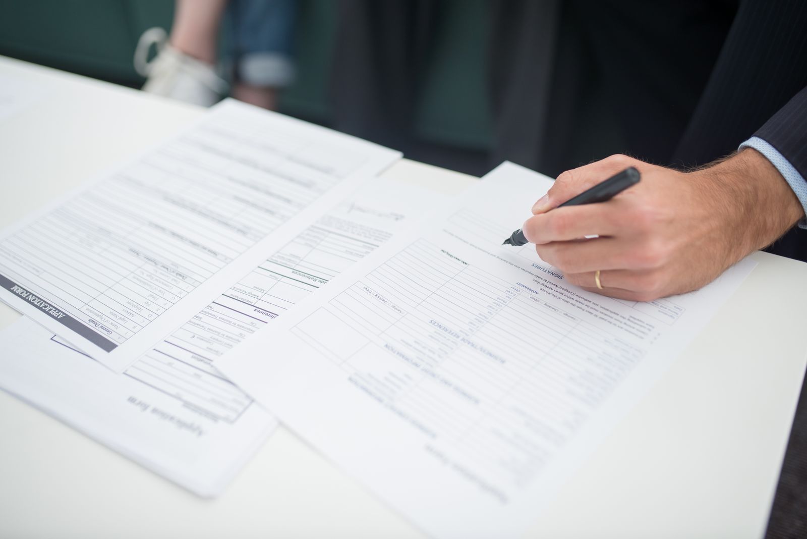 Close-up of a hand signing an insurance claim document at a desk