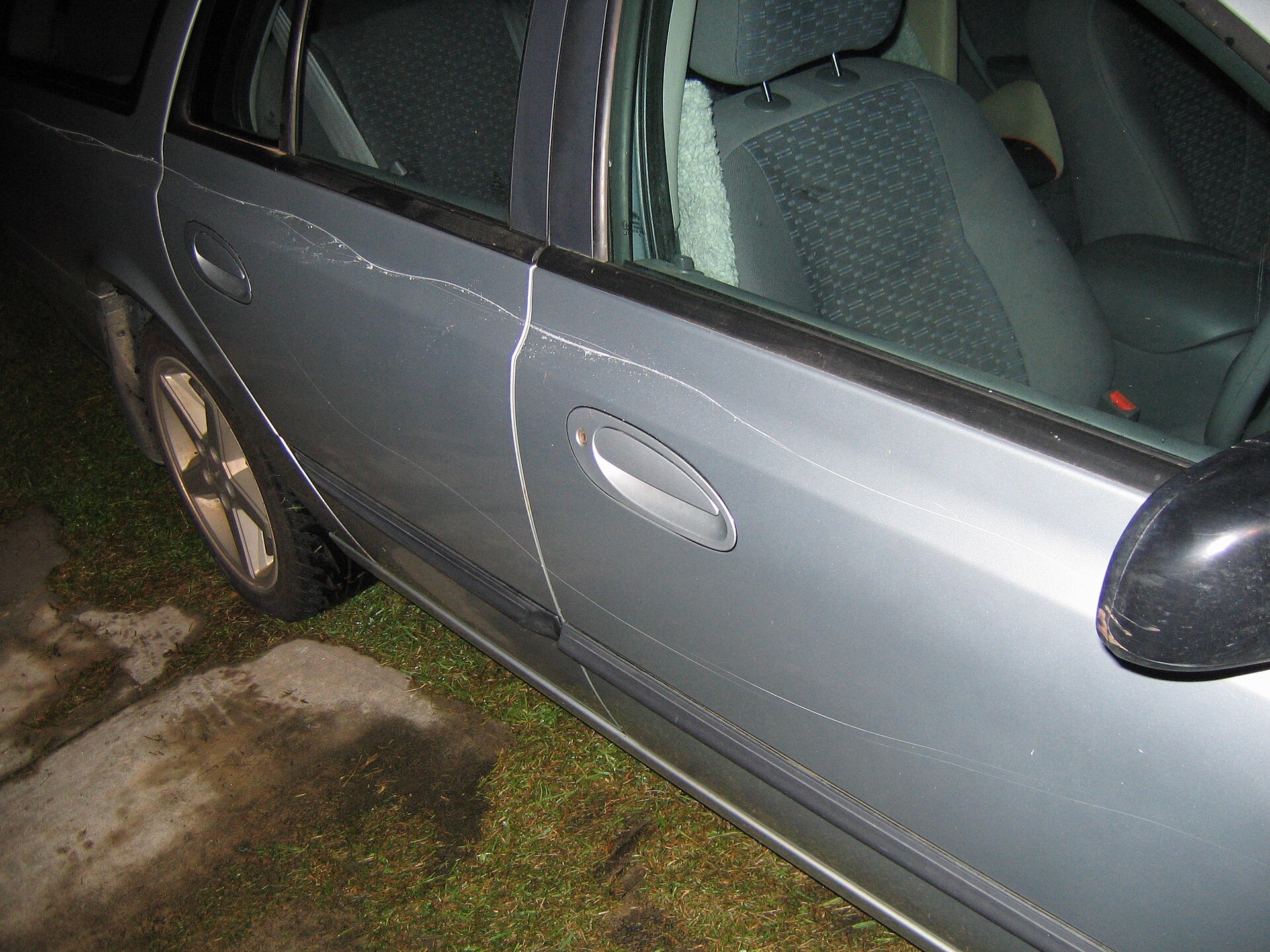 Long deliberate scratch marks keyed into the side paint of a car by a vandal