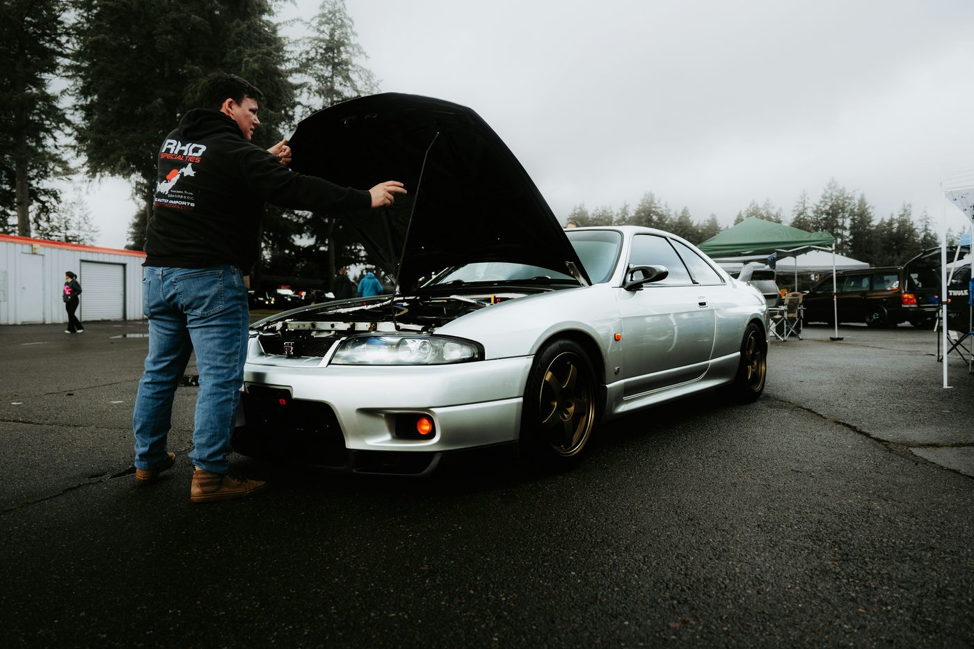 A man inspecting a car engine with the hood open