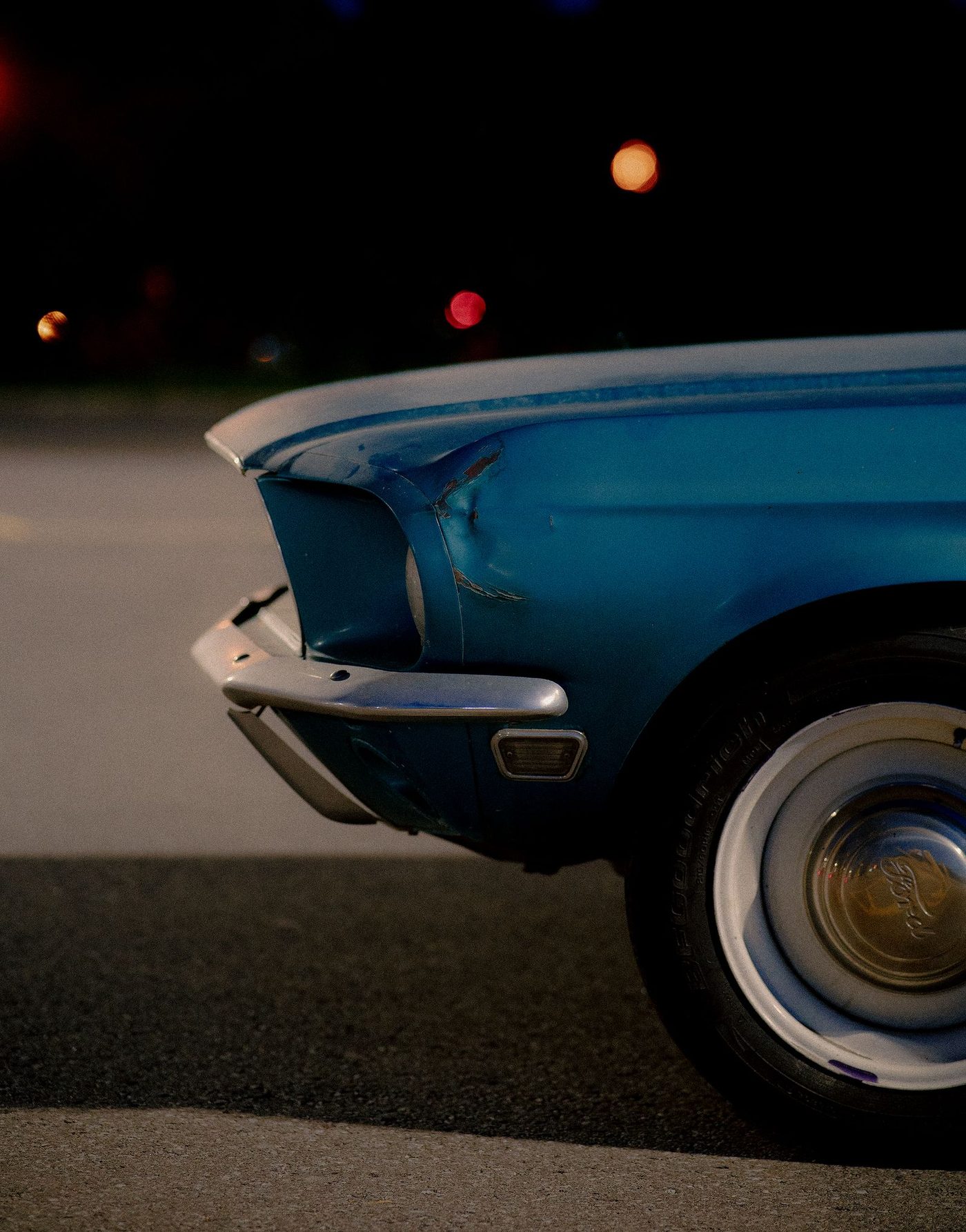 Close-up of a small crease dent with chipped paint on the rear fender of a vintage car