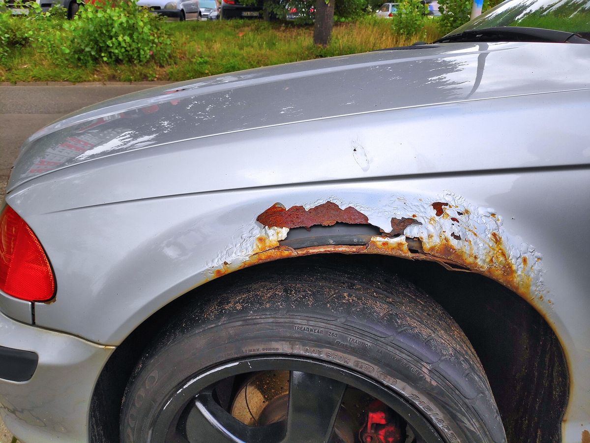 Rust bubbles that have perforated the bodywork on a car, exposing holes in the metal