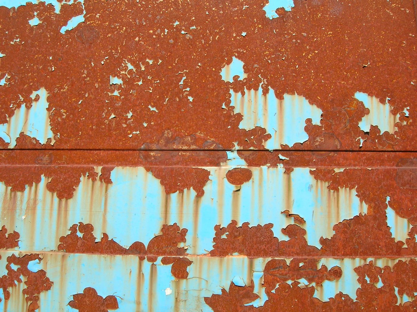 Close-up of paint lifting and cracking over rust on a vehicle body panel